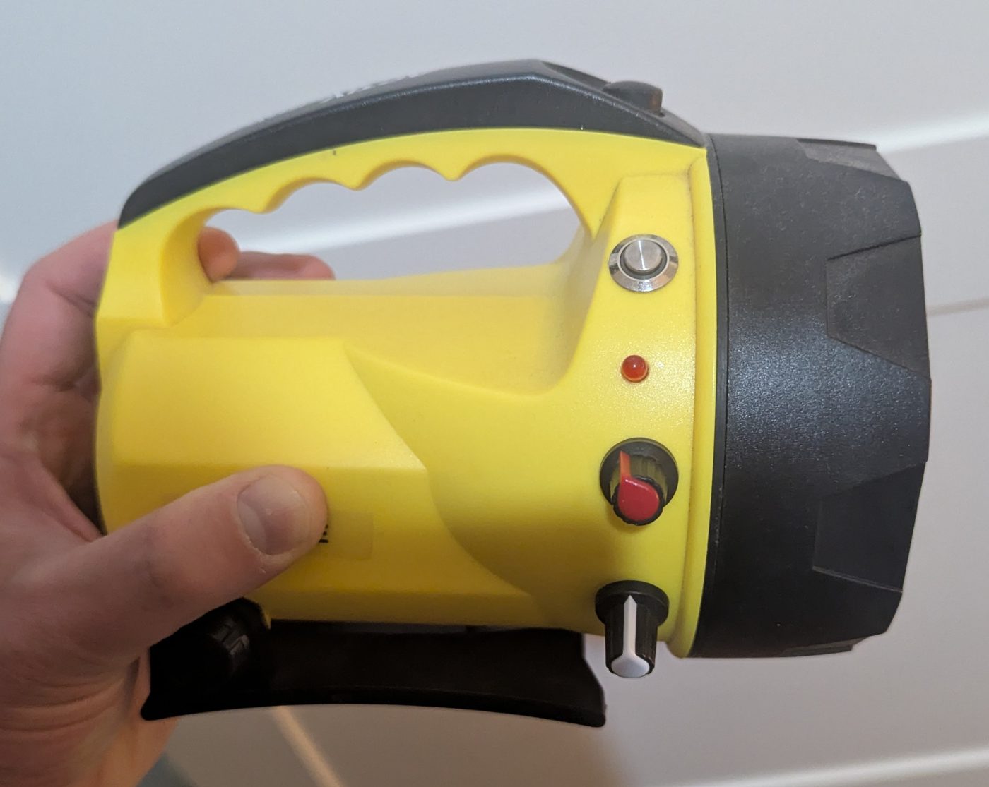 Yellow lantern torch with a silver push button, a small red LED, a red knob and a white knob on the side