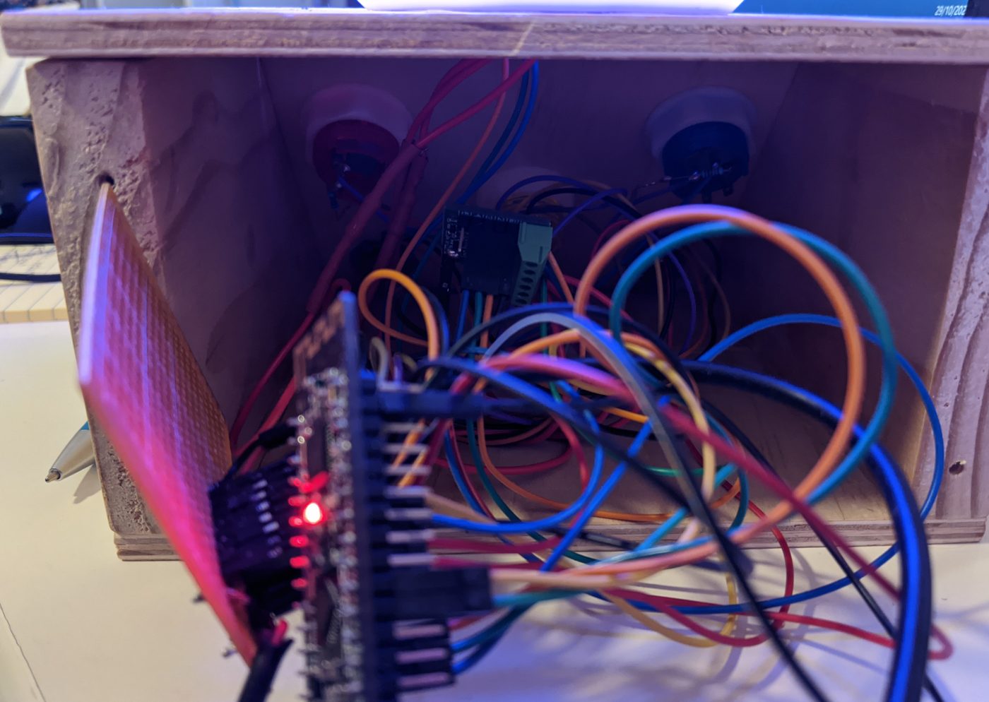 Colourful jumper wires inside the plywood night light box connecting the buttons to the Arduino