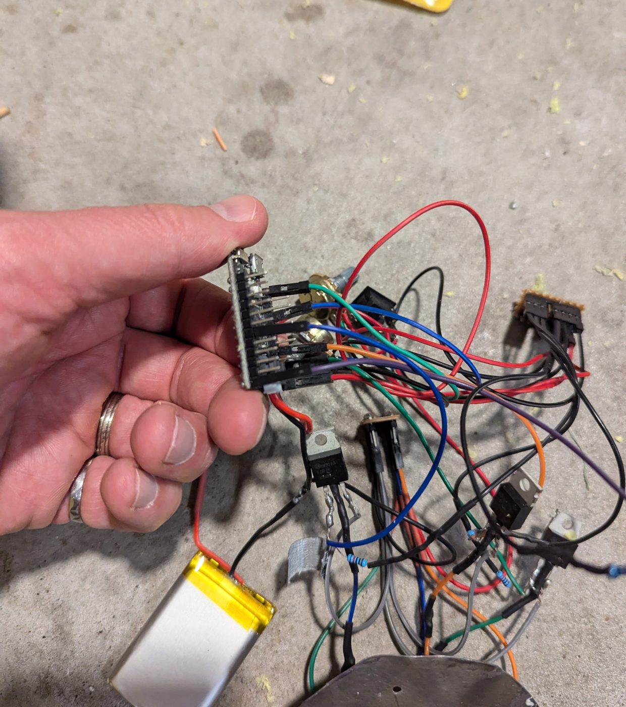 Holding the Qduino Mini board with wires running to the MOSFETs, LiPo battery and LED